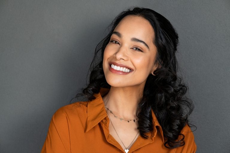 mujer adulta sonriente gracias a los beneficios de las carillas dentales