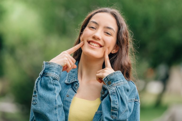 mujer joven formando con sus dedos una sonrisa feliz en su rostro