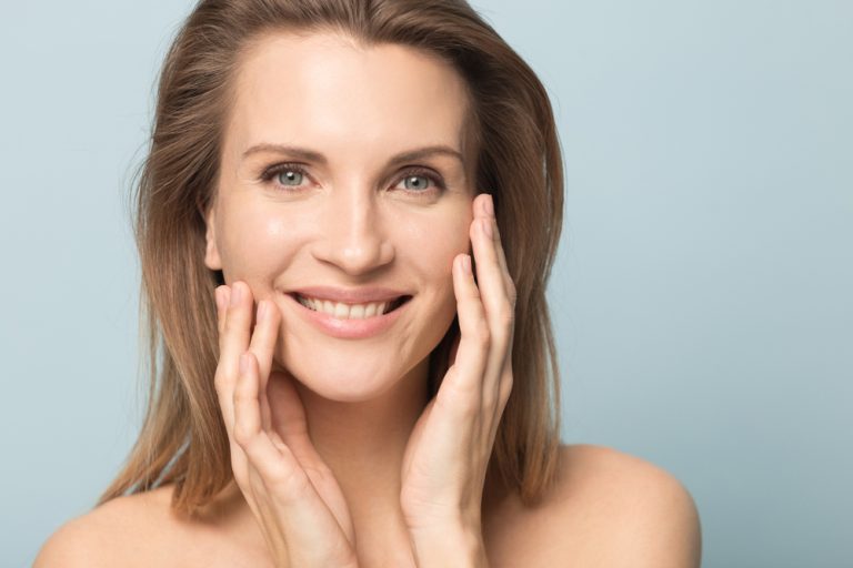 mujer sonriente que luce un rostro más joven usando bioestimuladores de colágeno